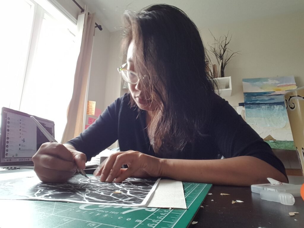 Elaine Joy using a pen knife to work a paper cutting art piece.